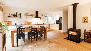Een moderne keuken met een centraal eiland, houten stoelen, een fornuis en een eethoek.