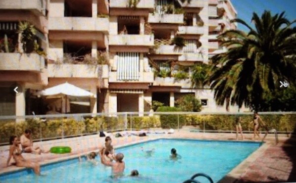 A swimming pool surrounded by a multi-story building with balconies.
