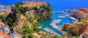 A coastal town with a historic castle on a cliff overlooking a marina filled with boats.