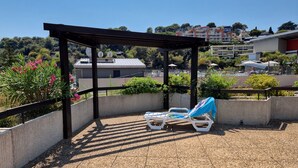 A rooftop terrace with two lounge chairs, a pergola, and a view of surrounding buildings. - Studio in Residence with swimming pool and solarium, 5 minutes from the beach (Roquebrune-Cap-Martin)