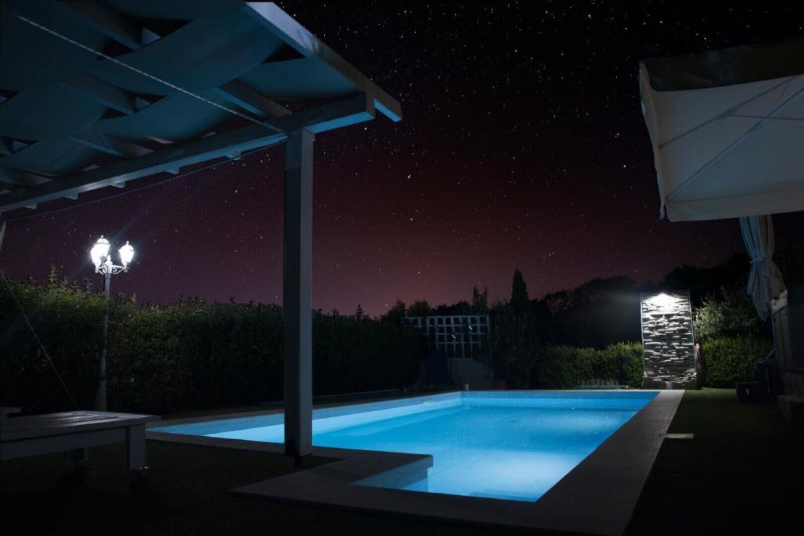A swimming pool at night with a starry sky above.