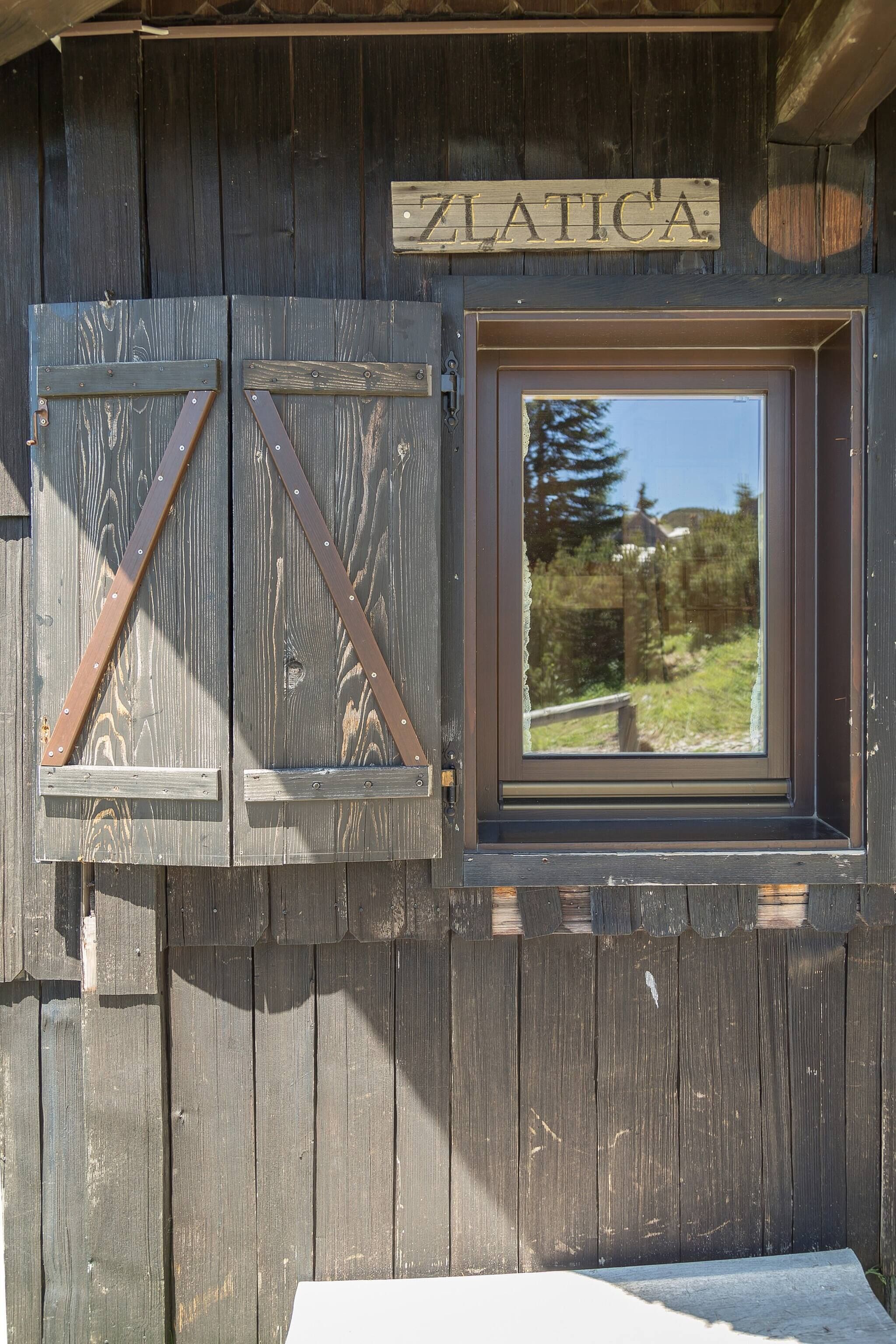 A wooden cabin with a sign reading "ZLATICA" above a window.