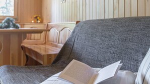 A cozy room with wooden walls, a bench, a sofa with a book, and a pendant light. - Stunning Views - Chalet Encijan - Velika Planina (Kamnik)
