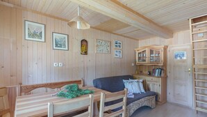 A wooden interior with a dining table, chairs, a sofa, and a cabinet with glass doors. - Stunning Views - Chalet Encijan - Velika Planina (Kamnik)