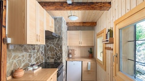 Eine kleine Küche mit Holzausstattung, einer Steinwand, einem eingebauten Backofen und einem weißen Kühlschrank.
