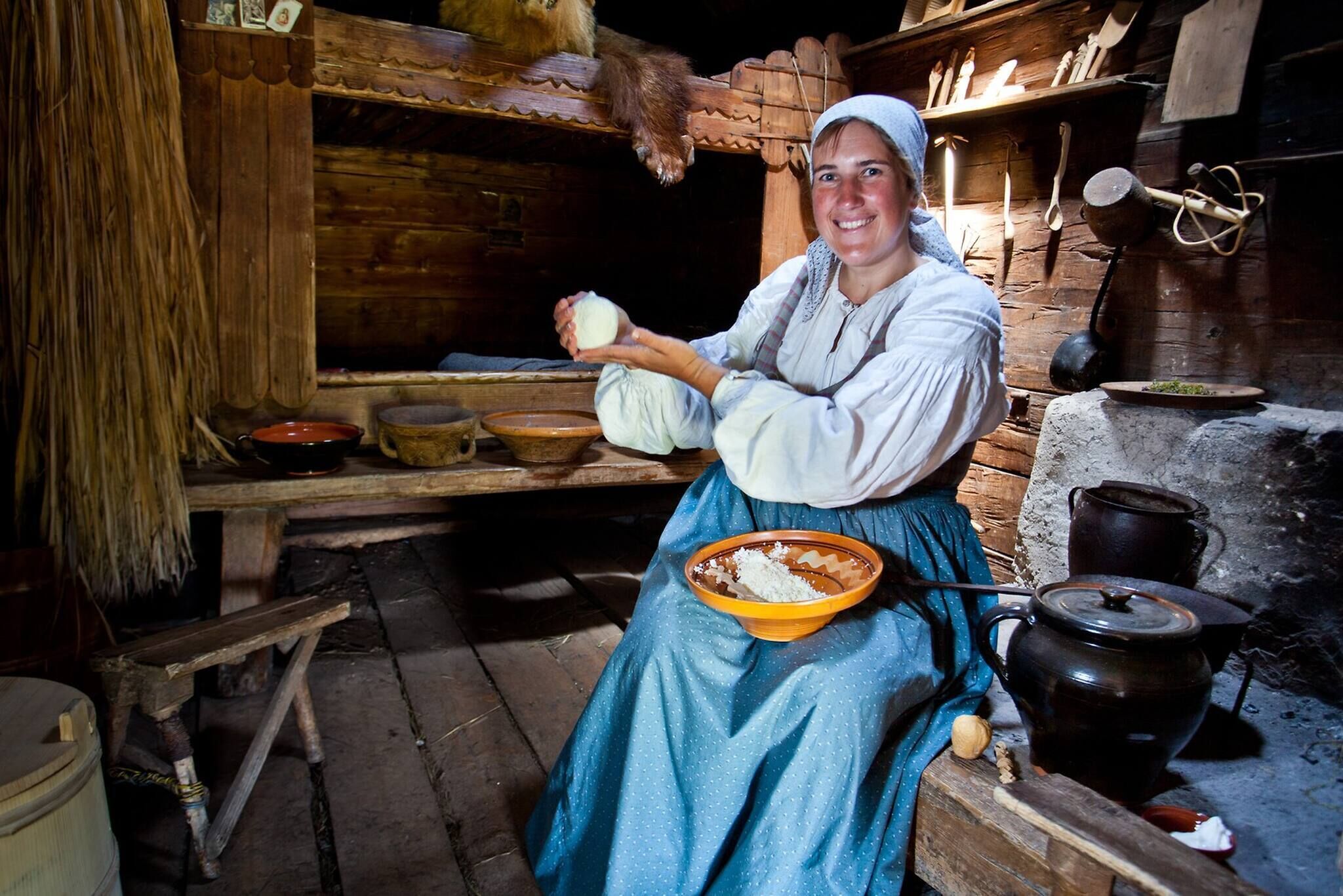 A rustic kitchen with wooden shelves, a large pot, and a bowl of food.