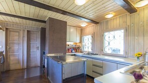 A kitchen with wooden cabinets, a central island, and a window with decorative glass. - Chalet Pehta - Velika Planina (Kamnik)