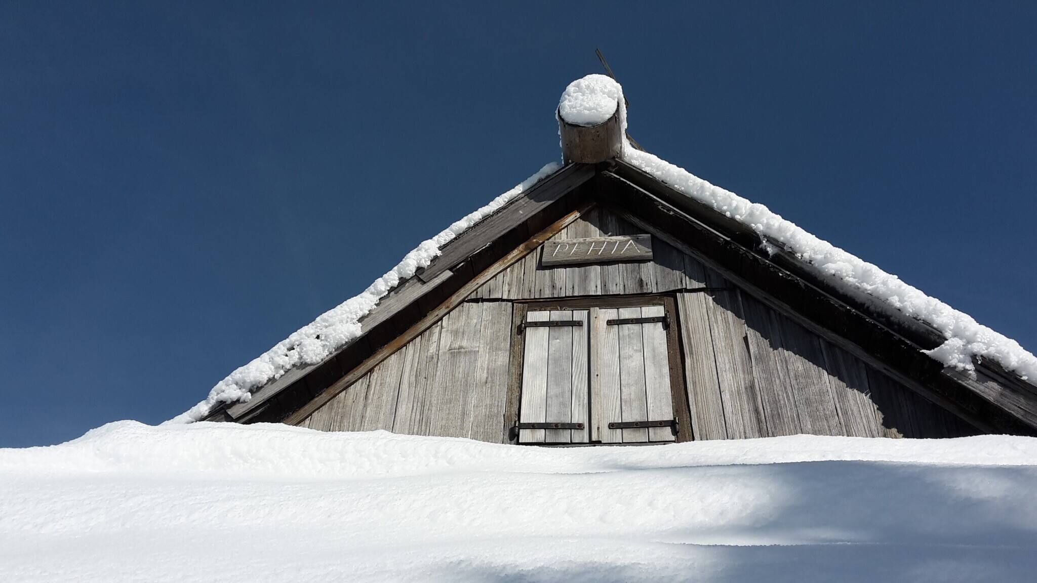 A wooden cabin with a snow-covered roof and a chimney.