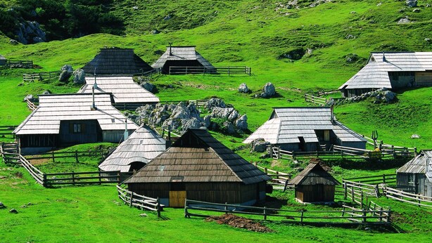 A rural landscape with several wooden farm buildings surrounded by fences. - Chalet Pehta - Velika Planina (Kamnik)