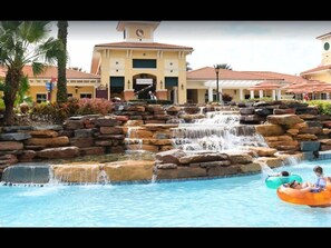 Um hotel com área de piscina, apresentando uma cascata e boias infláveis.