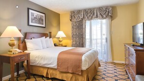 Une chambre d’hôtel avec un grand lit, deux tables de chevet avec des lampes, une commode, un téléviseur et une moquette à motifs.