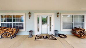 A front entrance with a double door, two windows with blinds, and a welcome mat with a monogram.