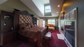 A spacious bedroom with a large bed, a seating area with a sofa, and a television.