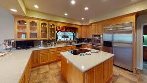 A modern kitchen with wooden cabinets, a stainless steel refrigerator, and a central island.
