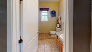 A bathroom with a toilet, sink, and window. - Exquisite Mountain Mansion West Wing (Silver City)