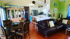 A spacious living room with a dark leather sofa, a dining table with chairs, and a kitchen area with white cabinets and a refrigerator. - Luxury Oceanview Pool Eco-friendly Villa Near Key West (Summerland Key)