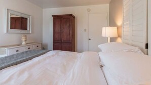 Une chambre d’hôtel comprenant un lit, une commode, un miroir, une armoire et une lampe.
