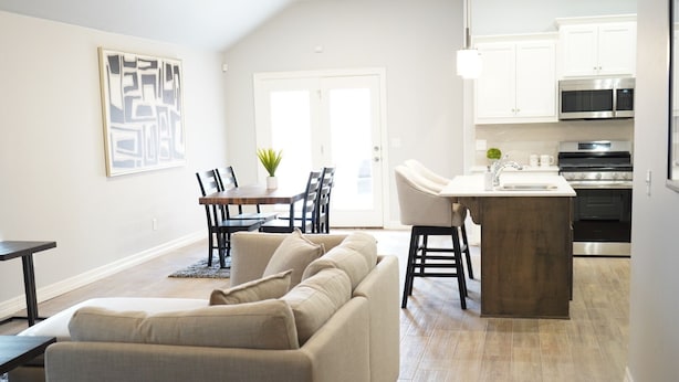 A modern living room with a sofa, dining table, and kitchen area with appliances. - The Cosmopolitan Modern, Cozy, New 3bedroom Home (Yukon)