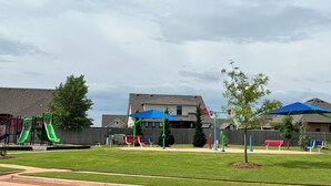A residential area with a playground, benches, and a house in the background. - The Cosmopolitan Modern, Cozy, New 3bedroom Home (Yukon)