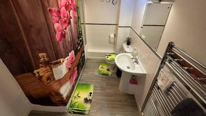 A modern bathroom with a shower curtain, toilet, sink, and mirror. - London - 2 Bed Flat - Sleeps 4 - Parking - Wifi (London)