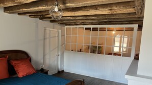 Un dormitorio con techo de madera, una cama con colcha azul, almohadas rojas y ventana con vista al exterior.