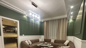 Una sala de estar moderna con un sofá seccional, una mesa redonda y un área de comedor visible a través de un vano abierto.