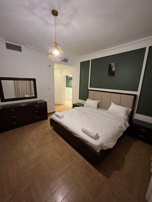 Relax in a serene space with a large bed, bedside tables, and a stylish pendant light.