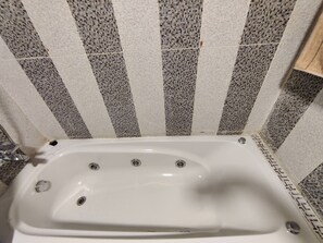 Bathroom features a bathtub with a striped tile pattern on the walls.