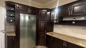 Una cocina con armarios de madera oscura, un refrigerador de acero inoxidable y una encimera de mármol.