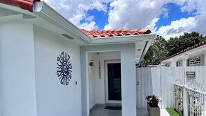Um edifício branco com telhado de telhas vermelhas, cerca branca e aviso de 'Cuidado com o cão'.