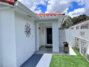 A white building with a red-tiled roof, a white fence, and a 'Beware of Dog' sign.