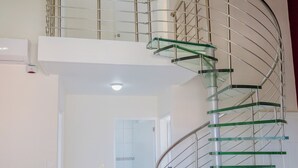 A modern spiral staircase with glass steps and metal railings, leading to an upper floor. - Spacious 4-bedroom Apartment 2 km From Eagle Beach (Noord)