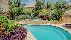 Una piscina rodeada de exuberante vegetación tropical y una estructura de piedra.