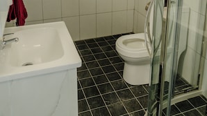 Un baño con una bañera blanca, un inodoro y una ducha con mampara de vidrio.