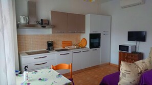 A compact kitchen with white cabinets, a coffee maker, a microwave, and a TV. - Fantastic House Near to the Beach (Rab)