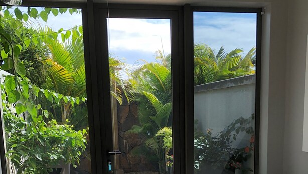 A bathroom with a bathtub, a shower, and a door leading to a garden with plants and a gravel path. - Royal Park Villa De Luxe 3 Chambres (Balaclava)