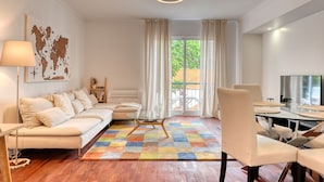 A modern living room with a sofa, a glass coffee table, and a dining area with chairs.