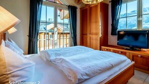 Une chambre à coucher avec un lit, une armoire en bois, une télévision et une fenêtre donnant sur une vue sur la montagne.