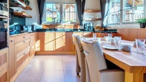 Une cuisine moderne avec des meubles en bois, un four encastré et un coin repas comprenant une table et des chaises.