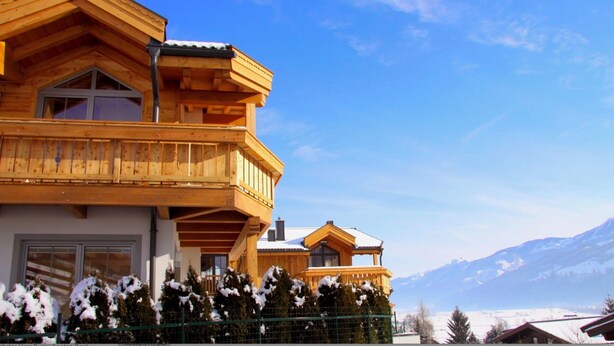 Un chalet en bois doté d’un balcon, d’un deuxième balcon à l’étage, et offrant une vue sur la montagne.