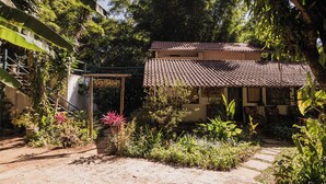 A rustic house with a tiled roof, surrounded by lush greenery and a stone pathway. - Pousada Passaredo (Brumadinho)