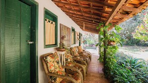 A covered outdoor seating area with wicker chairs and a potted plant. - Pousada Passaredo (Brumadinho)