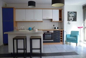 Eine moderne Küche mit weißen Schränken, einem blauen Kühlschrank und einer zentralen Kochinsel mit Hockern.