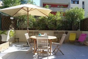 Relax in the serene outdoor patio surrounded by lush greenery and a stylish umbrella.