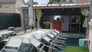 Ein Poolbereich mit Liegestühlen, einer kleinen Küche und einem grünen Rasen.