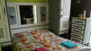 Ein Schlafzimmer mit einem Bett, einem Schminktisch, einem Spiegel und einem Wandregal.
