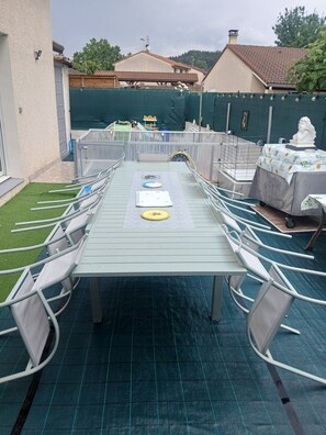 An outdoor patio with a long table, chairs, and a statue on a table. - Magnifique Maison Toute Pratrique (Crest)