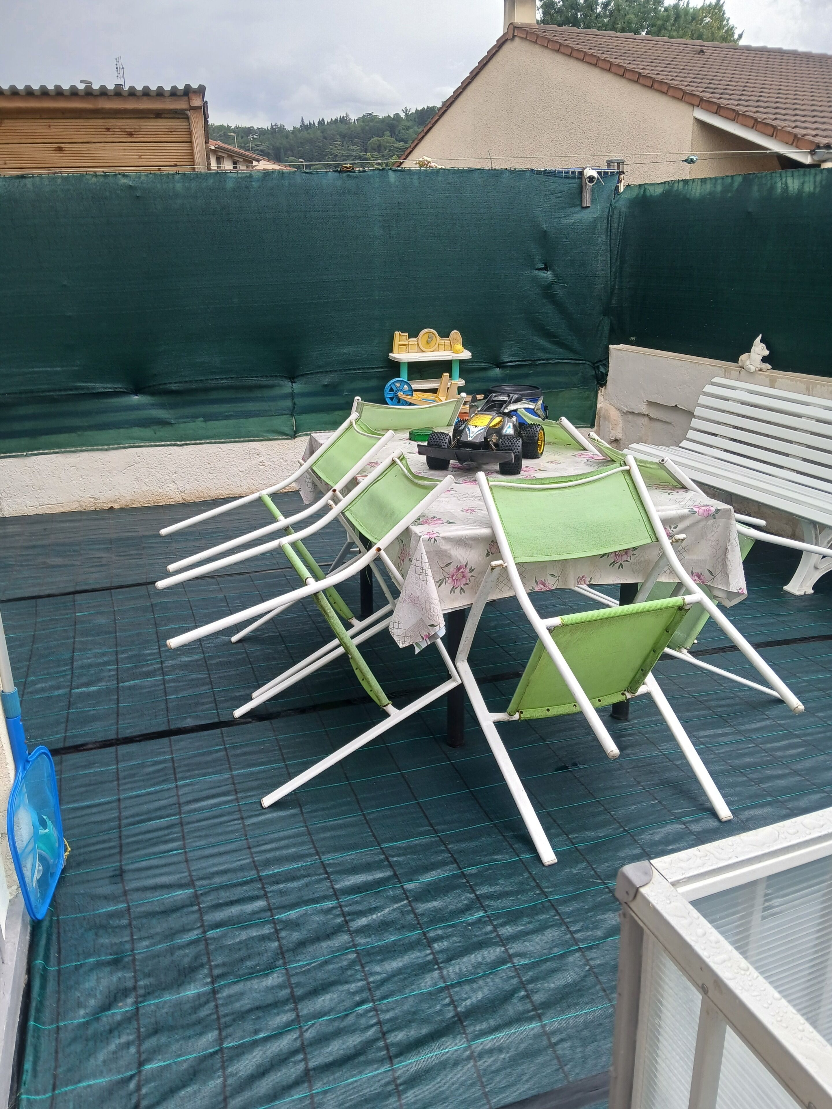 Un espacio exterior techado con una mesa y sillas, un coche de juguete y una maqueta de barco.