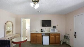 A compact kitchen with wooden cabinets, a microwave, a small refrigerator, and a ceiling fan. - OYO Hotel Yuma AZ - I-8/us-95 (Yuma)