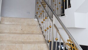 A staircase with beige tiles, a metal railing with golden accents, and a framed picture on the wall. - 3A Lodge (Lekki)